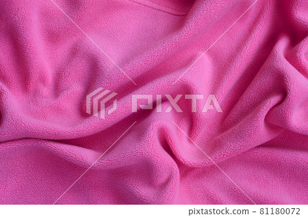 The blanket of furry pink fleece fabric. A background of light pink soft plush fleece material with a lot of relief folds The blanket of furry pink fleece fabric. A background of light pink soft plush fleece material with a lot of relief folds 81180072