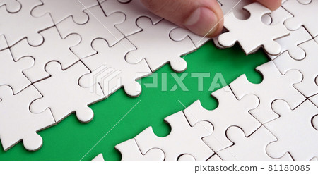 The human hand paves the way to the surface of the jigsaw puzzle, forming a green space. The concept of overcoming the difficulties on the way to success The human hand paves the way to the surface of the jigsaw puzzle, forming a green space. The concept of overcoming the difficulties on the way to success 81180085