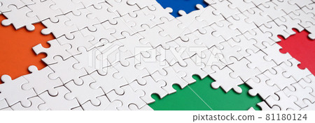 Close-up texture of a white jigsaw puzzle in assembled condition with missing elements, under which surfaces of different colors Close-up texture of a white jigsaw puzzle in assembled condition with missing elements, under which surfaces of different colors 81180124