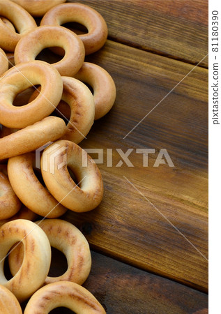 A lot of fresh yellow bagels lie on the surface of the old dark wood. A popular kind of flour products. One of the traditional Russian treats for tea A lot of fresh yellow bagels lie on the surface of the old dark wood. A popular kind of flour products. One of the traditional Russian treats for tea 81180390