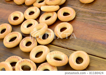 A lot of fresh yellow bagels lie on the surface of the old dark wood. A popular kind of flour products. One of the traditional Russian treats for tea A lot of fresh yellow bagels lie on the surface of the old dark wood. A popular kind of flour products. One of the traditional Russian treats for tea 81180424