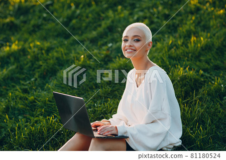 Millenial young woman blonde short hair outdoor smiling portrait with laptop. Millenial young woman blonde short hair outdoor smiling portrait with laptop. 81180524