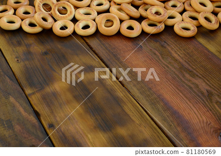 A lot of fresh yellow bagels lie on the surface of the old dark wood. A popular kind of flour products. One of the traditional Russian treats for tea A lot of fresh yellow bagels lie on the surface of the old dark wood. A popular kind of flour products. One of the traditional Russian treats for tea 81180569