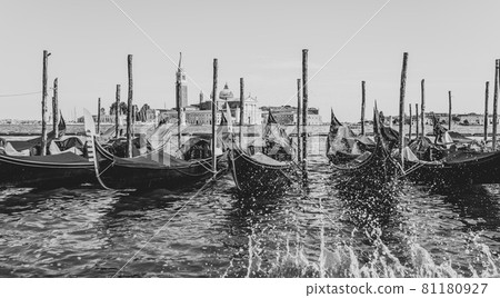 Moored gondolas at St. Mark Square with Church of San Giorgio Maggiore on background. Venice, Italy. Black and white image. Moored gondolas at St. Mark Square with Church of San Giorgio Maggiore on background. Venice, Italy. Black and white image. 81180927