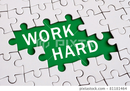 White jigsaw puzzle in assembled state with missing elements forming a green space with white inscription. Work hard White jigsaw puzzle in assembled state with missing elements forming a green space with white inscription. Work hard 81181464