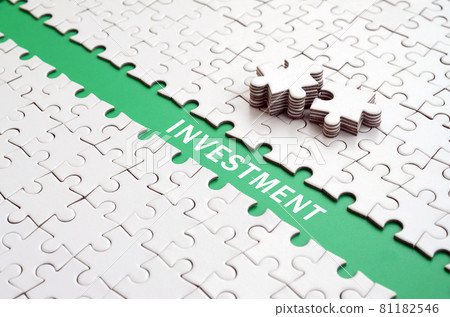 Investment. The green path is laid on the platform of a white folded jigsaw puzzle. The missing elements of the puzzle are stacked nearby Investment. The green path is laid on the platform of a white folded jigsaw puzzle. The missing elements of the puzzle are stacked nearby 81182546