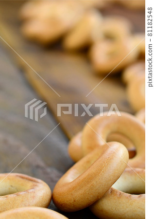 A lot of fresh yellow bagels lie on the surface of the old dark wood. A popular kind of flour products. One of the traditional Russian treats for tea A lot of fresh yellow bagels lie on the surface of the old dark wood. A popular kind of flour products. One of the traditional Russian treats for tea 81182548