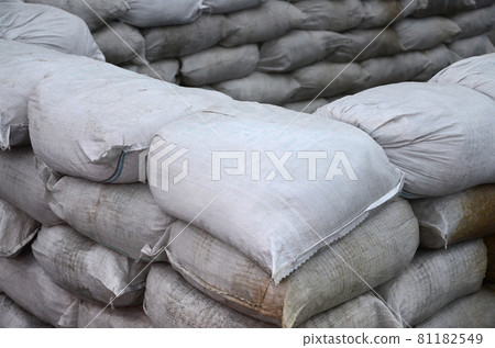 Background of many dirty sand bags for flood defense. Protective sandbag barricade for military use. Handsome tactical bunker Background of many dirty sand bags for flood defense. Protective sandbag barricade for military use. Handsome tactical bunker 81182549