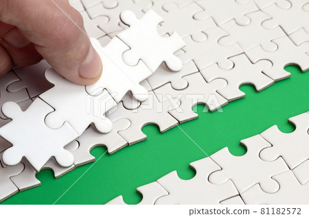 The human hand paves the way to the surface of the jigsaw puzzle, forming a green space. The concept of overcoming the difficulties on the way to success The human hand paves the way to the surface of the jigsaw puzzle, forming a green space. The concept of overcoming the difficulties on the way to success 81182572