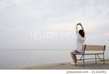 A woman looking at the sea on a bench at Matama Coast at high tide in the morning 81182891