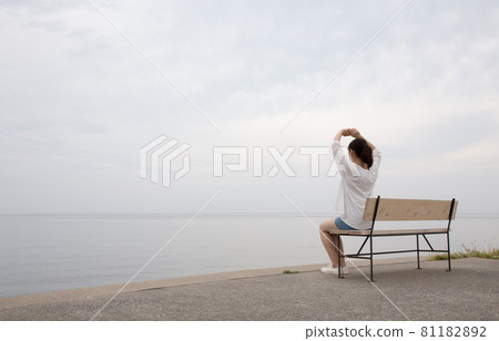 A woman looking at the sea on a bench at Matama Coast at high tide in the morning 81182892