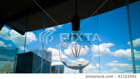 Round glass light bulb on a background of blue sky with clouds. Concept image. Round glass light bulb on a background of blue sky with clouds. Concept image. 81183092