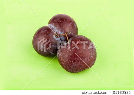 Two ripe juicy plums on a green background. Two ripe juicy plums on a green background. 81183525