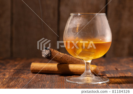 Glass of whisky and lighted cigar in an ash tray 81184326