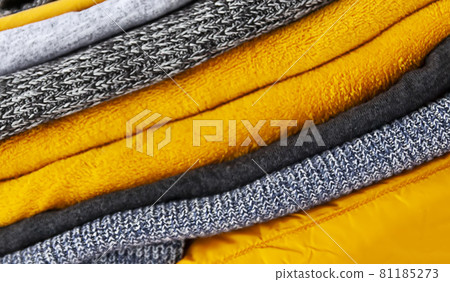 Pile of the grey and yellow warm knitted sweaters and jumpers close up Pile of the grey and yellow warm knitted sweaters and jumpers close up 81185273