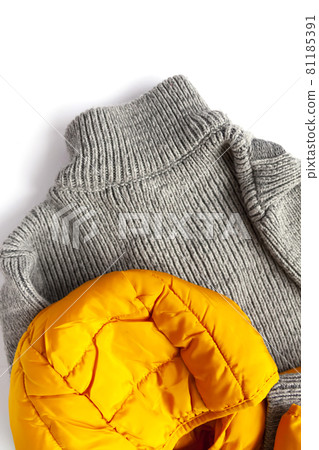 Warm yellow jacket and woolen knitted jumper on white background. Fashion outfit. Bright trendy colors. Home storage. Small space organizing. Warm yellow jacket and woolen knitted jumper on white background. Fashion outfit. Bright trendy colors. Home storage. Small space organizing. 81185391