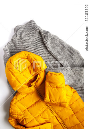Warm yellow jacket and woolen knitted jumper on white background. Fashion outfit. Bright trendy colors. Home storage. Small space organizing. Warm yellow jacket and woolen knitted jumper on white background. Fashion outfit. Bright trendy colors. Home storage. Small space organizing. 81185392