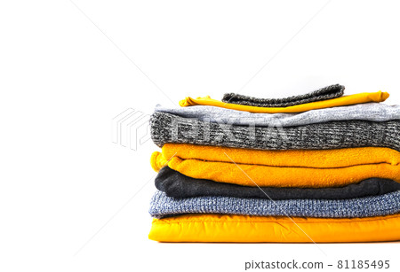 Pile of the warm knitted clothes. Warm yellow and grey sweaters and jumpers in stack on white background. Pile of the warm knitted clothes. Warm yellow and grey sweaters and jumpers in stack on white background. 81185495
