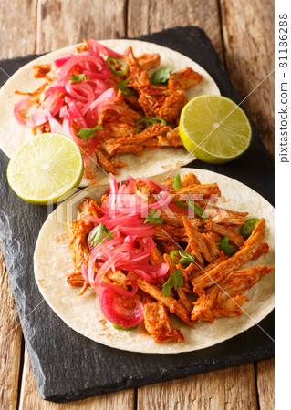 Citrus braised pork shoulder making it tender and flavorful Cochinita Pibil with tortilla and marinated onion closeup in the slate board. Vertical Citrus braised pork shoulder making it tender and flavorful Cochinita Pibil with tortilla and marinated onion closeup in the slate board. Vertical 81186288