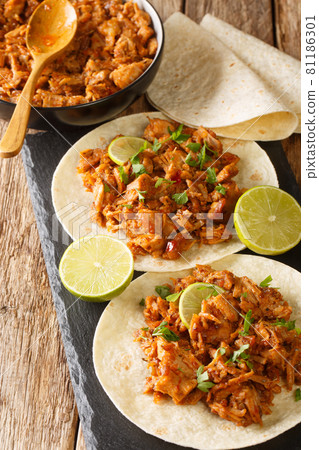 Chilorio is a pork dish from the Mexican state of Sinaloa served with tortilla and lime closeup in the slate board. Vertical 81186301