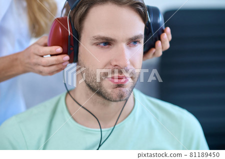 Tranquil patient wearing headsets during a hearing screening procedure 81189450
