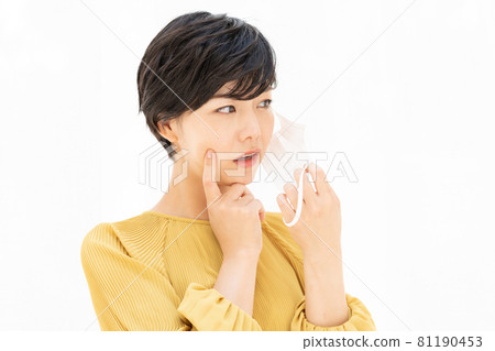 A young woman suffering from rough skin caused by a mask in front of a white curtain A young woman suffering from rough skin caused by a mask in front of a white curtain 81190453