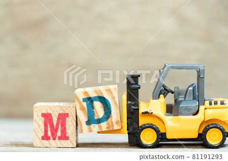 Toy forklift hold letter block d to complete word MD (abbreviation of doctor of medicine or managing director) on wood background 81191293