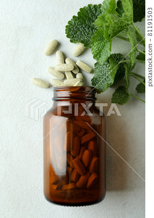 Bottle with herbal pills on white textured background, top view Bottle with herbal pills on white textured background, top view 81191503
