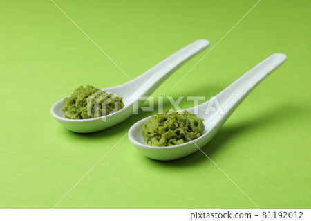 Ceramic spoons with wasabi on green background 81192012