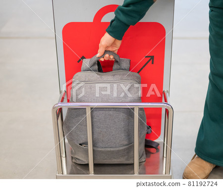 Woman checking backpack metal cage checking carry-on luggage at airport. Woman checking backpack metal cage checking carry-on luggage at airport. 81192724