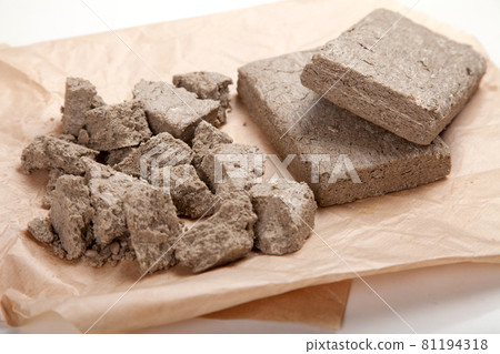 Halva in briquettes and in large pieces lies on craft paper. Halva in briquettes and in large pieces lies on craft paper. 81194318