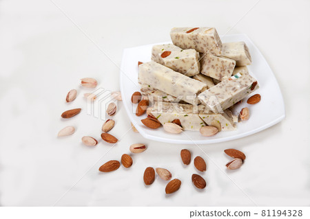 Halva made from sunflower seeds, almonds and pistachios lies on a plate on a white background. Copy spaes. Halva made from sunflower seeds, almonds and pistachios lies on a plate on a white background. Copy spaes. 81194328