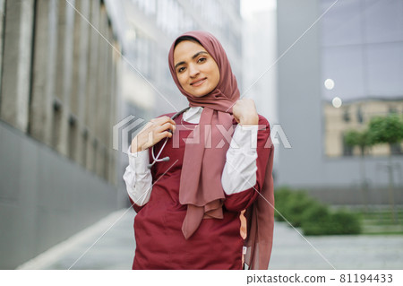Arab female doctor or medical student, posing and smiling, standing outside modern clinic Arab female doctor or medical student, posing and smiling, standing outside modern clinic 81194433