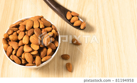 Almond nuts in a white bowl on wooden background, top view, flat lay, top-down, selective focus.copy space. 81194958