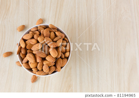 Almond nuts in a white bowl on wooden background, top view, flat lay, top-down, selective focus.copy space. 81194965