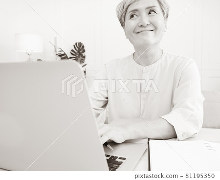 A mature woman in Asia uses an electronic computer to write at home. A mature woman in Asia uses an electronic computer to write at home. 81195350