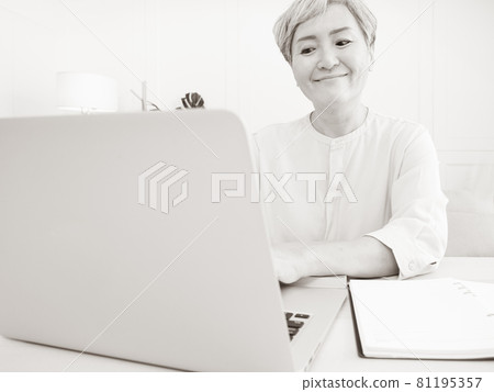 A mature woman in Asia uses an electronic computer to write at home. 81195357