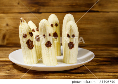 Homemade Halloween scary banana ghosts monsters with chocolate faces. Funny dessert for Halloween party on wooden table Homemade Halloween scary banana ghosts monsters with chocolate faces. Funny dessert for Halloween party on wooden table 81196750