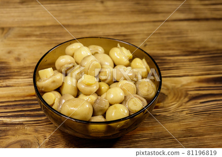 Glass bowl with pickled champignons. Marinated mushrooms on wooden table 81196819