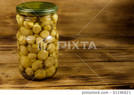 Delicious marinated mushrooms in glass jar on wooden table 81196821