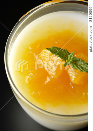 A bird's-eye view of almond tofu with mango sauce containing pulp on a black background 81200964