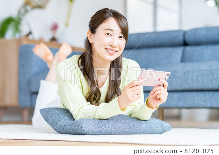 A young woman watching a video on her smartphone A young woman watching a video on her smartphone 81201075