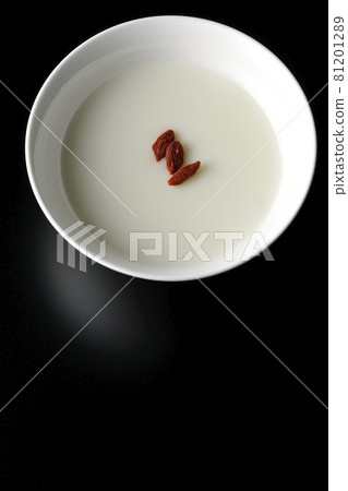 A bird's-eye view of a simple almond tofu with goji berries on a black background A bird's-eye view of a simple almond tofu with goji berries on a black background 81201289