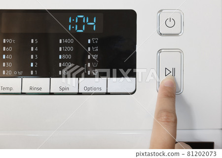 Close-up of female hand touching digital screen, automatic washing machine control panel, start or pause button. 81202073