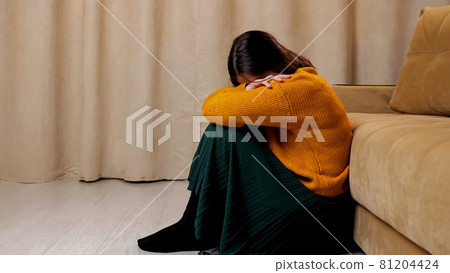 Depressed lady in sweater and skirt sits on wooden floor 81204424