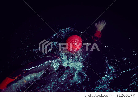 triathlon athlete swimming in dark night wearing wetsuit 81206177