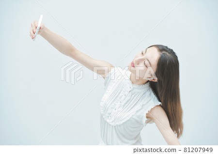 一個年輕女子拿著智能手機跳舞 81207949