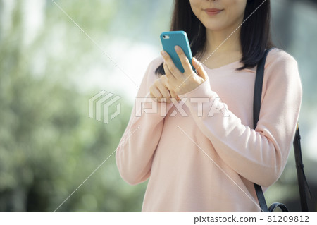 A woman looking at a smartphone outdoors 81209812