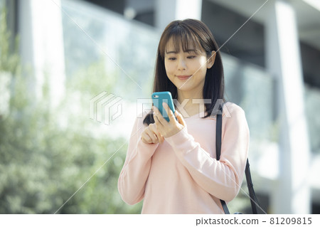 A woman looking at a smartphone outdoors A woman looking at a smartphone outdoors 81209815