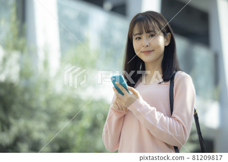 A woman looking at a smartphone outdoors A woman looking at a smartphone outdoors 81209817